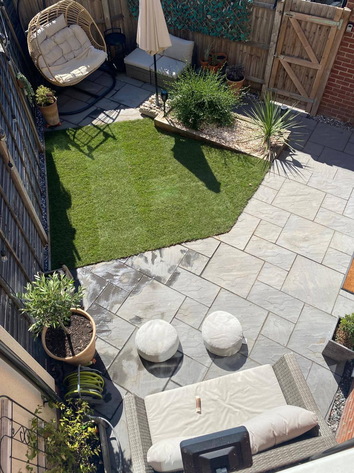 Aerial view of sandstone patio and artificial lawn with rattan seating and hanging chair