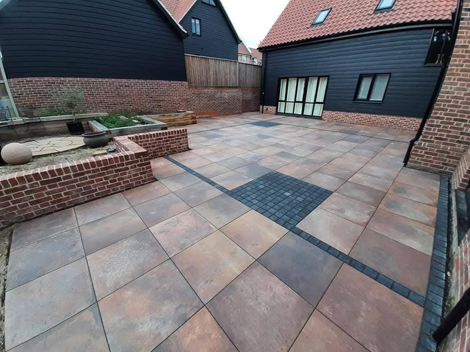 Large rust porcelain patio with cobblestone inlay and raised brick planter